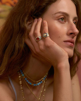 Model wearing multiple rings and necklaces 