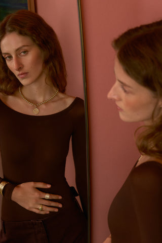 Model wearinng necklace and rings in mirror