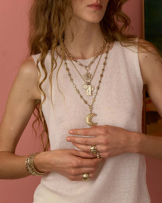 Woman wearing gold jewelry including necklaces, bracelets, and rings 