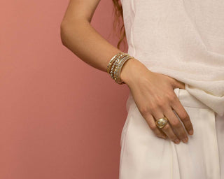 Model wearing gold bracelets and a ring