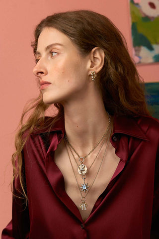 Model wearing layered necklaces and earrings