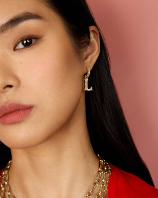Close-up of a model wearing southwestern hoops with initial charms
