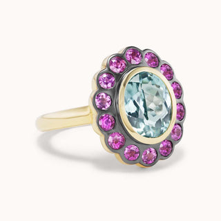 Ring with a central blue gemstone surrounded by pink gemstones 